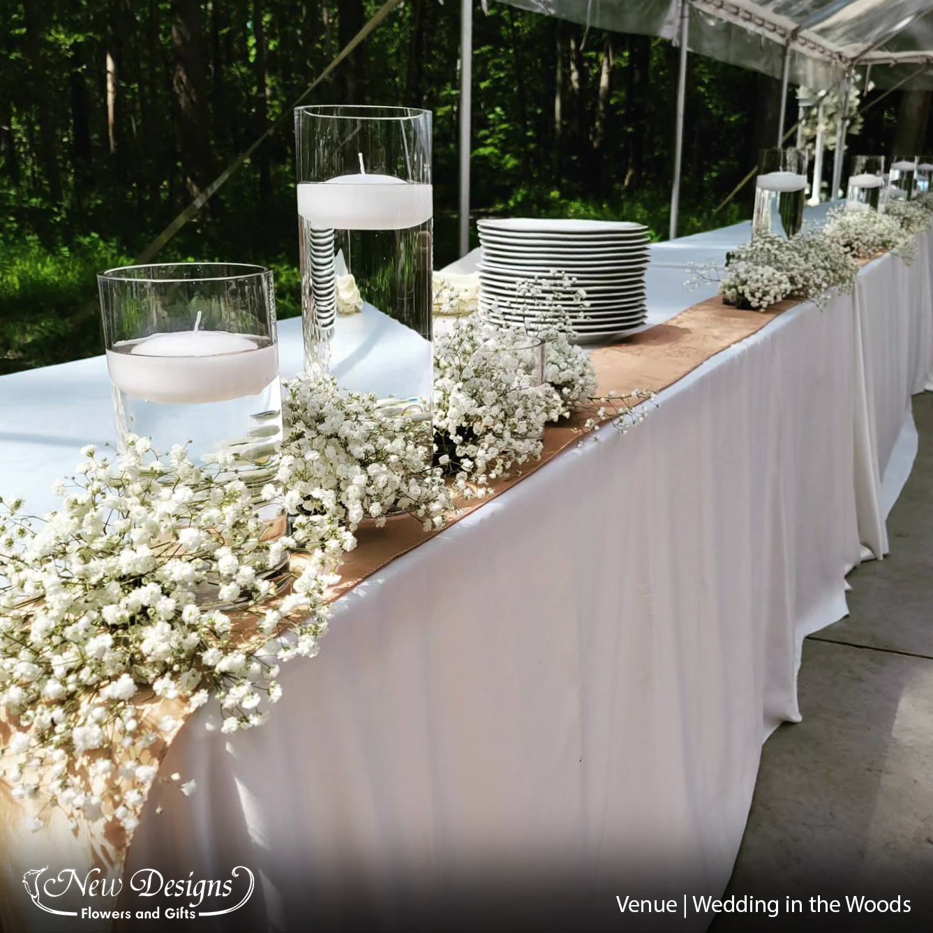 Fluffy clouds of babies breath line a buffet table, around tall pillar vases with floating candles.